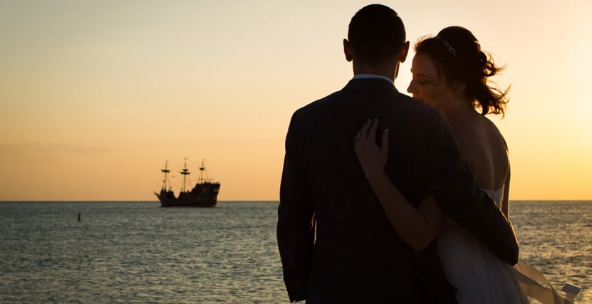 Couple embracing at sunset on Sand Key Beach with Clearwater Pirate Ship in the background